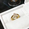 Primo piano di un elegante anello dorato con fiore di zircone in una scatola bianca - Oro