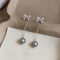 Close-up of minimalist silver needle bow stud earrings with zircon and grey pearl tassels - Bow Tassel / Gray
