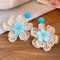 Detailed macro view of handmade beige raffia flower earrings with light blue fabric centers - Flower Style (HE34251) / Blue