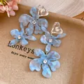 Close-up of light blue marbled acetate flower earrings with clear heart-shaped studs - Flower Tassel Drop Earrings / Blue