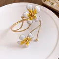Detailed close-up of a vintage gold-plated arm cuff with white and yellow enamel flower design - White