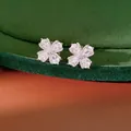 Close-up of silver-tone flower clip earrings with pear-shaped cubic zirconia on green velvet. - Clip-On Earrings / Silver