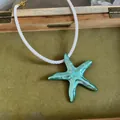 Gros plan d'un pendentif étoile de mer turquoise sur un collier en cordelette blanche. - Collier Seul (Sans Boucles d'Oreilles) / Bleu sarcelle