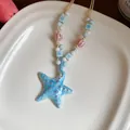 Macro shot of a handmade blue ceramic starfish necklace with colorful beads on a plate - Blue