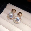 Detailed macro view of square crystal earrings with rhinestone halo in gold finish - Brown