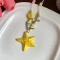 Close-up detail showing a vibrant yellow ceramic starfish pendant with colorful beads. - Yellow