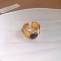 Gros plan d'une bague ouverte dorée vintage ornée d'une pierre ronde bleu foncé - Pierre Bleue Ronde (HR3664)