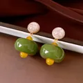 Dettaglio di orecchini vintage in resina verde con eleganti accenti dorati e perni - Verde & Giallo