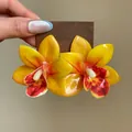 Gros plan de boucles d'oreilles orchidées jaunes avec un motif floral en résine. - Style de tige d'oreille en argent / Jaune