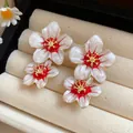 Close-up of elegant white and red enamel flower stud earrings in jewelry tray - Silver Earring Post Style / White-Red