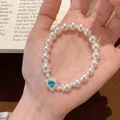 Elegant pearl bracelet detail with heart-shaped blue gemstone and delicate silver charm - Artificial Pearl Zirconia Heart Bracelet / White-Blue
