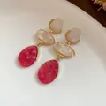 Détail de boucles d'oreilles vintage en résine avec élégante texture marbrée rouge et crème - Pendentif Goutte d'Eau Style Palais Vintage / Rose rouge