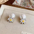 Detailed macro view of elegant daisy flower and large white pearl stud earrings set - Yellow