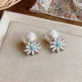 Close-up detail of sweet Korean style daisy flower pearl earrings with blue enamel center - Blue