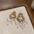Detailed view of ornate gold earrings with oval crystals and white pearl tassels - Oval Pearl Tassel Style / Gold