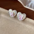 Dettaglio di orecchini a cuore in argento con motivo a farfalla e bordi incisi - Argento