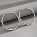 Close-up detail of silver-tone large hoop earrings with elegant diamond-cut texture - Silver