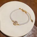 Gros plan d'un élégant bracelet en perles avec un pendentif étoile à huit branches en zircon. - Or+Blanc