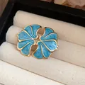 Close-up detail of vintage blue enamel flower earrings with elegant gold-plated edges. - Blue