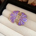 Detailed macro view of vintage purple enamel flower stud earrings with gold trim. - Purple