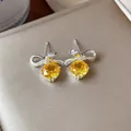 Dettaglio ravvicinato di eleganti orecchini a fiocco con zirconi gialli sfaccettati - Perno in Argento-Argento-Giallo