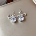 Primo piano di eleganti orecchini a lobo con fiocco d'argento e zirconi tondi scintillanti. - Argento & Bianco (Silver Earring Post)