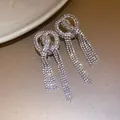 Close-up of sparkling rhinestone bow-knot tassel earrings with elegant drapes - Bowknot Tassel Studs / Silver