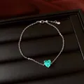 Vue détaillée d'un bracelet en argent avec un zircon cyan en forme de cœur sur un plateau noir - Bracelet / Argent-Vert