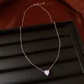 Gros plan d'un collier argenté avec pendentif cœur en zircon rose sur un plateau de présentation. - Collier / Argent
