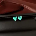 Vue macro de boucles d'oreilles en zircon cyan en forme de cœur sur une boîte à bijoux - Boucles d'oreilles clous / Vert