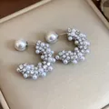 Close-up of elegant C-shaped silver earrings with delicate pearl and crystal details. - Silver