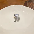 Dettaglio di un ear cuff a forma di orsetto con zirconi scintillanti e ciondolo a cuore - Clip (Singolo) / Argento