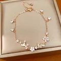 Detailed view of rose gold bracelet featuring crown, shell butterfly, and zircon flower charms - Gold