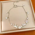 Detailed macro shot of an elegant silver bracelet with crown butterfly and flower charms - Silver