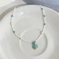 Dettaglio elegante di una collana di perle bianche con ciondolo in pietra turchese blu - Collana di Perle d'Acqua Dolce