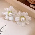 Close-up of elegant white fabric flower stud earrings with a central faux pearl. - White