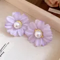 Close-up of purple fabric flower stud earrings with elegant pearl centers - Blue