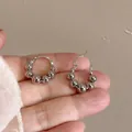 Detailed view of silver metallic beaded hoop earrings held in a hand for size scale - Ear Buckle / Silver