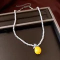 Close-up of pearl necklace featuring a bright yellow resin lemon pendant with zircon leaves. - Pearl Necklace / Silver/Yellow