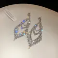 Nahaufnahme von funkelnden Strass-Ohrringen in Wassertropfenform mit elegantem Blatt-Hohl-Design. - Tropfen-Ohrhänger / Silber