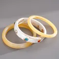 Dettaglio di tre braccialetti in resina marmorizzata con strass colorati su fondo grigio - Set Giallo E Bianco