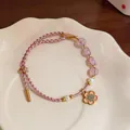 Detailed macro shot of hand-woven pink cord bracelet featuring pearls and cherry blossom charm - Flower Style