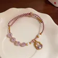 Close-up of handmade braided rope bracelet with pearls and gourd charm. - Gourd Style