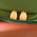 Detail van minimalistische 18k vergulde geborstelde metalen oorbellen op groen fluweel - Goud