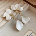 Macro view of vintage white enamel flower drop earrings placed inside a jewelry box - White