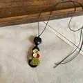 Detailed view of ethnic style necklace with wooden pendant, green tassel, and buttons - Oval Button Tassel Style(HN12316) / Coffee