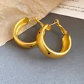 Close-up of elegant matte gold oval hoop earrings with stylish black polka dot accents. - Matte Gold Oval Hoop