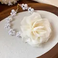 Detail of cream chiffon flower and pearl necklace on a rustic wooden tray - White