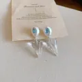 Vue macro d'élégantes boucles d'oreilles cônes avec pierre centrale bleue. - Bleu transparent
