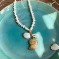 Close-up of ocean-themed necklace with shell and gold nautilus pendants on teal plate - Star Bead Chain Nautilus Necklace (3#)
